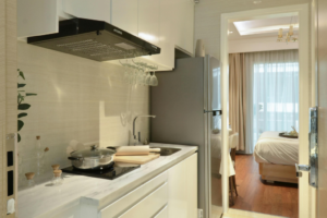 Cozinha compacta com depurador de ar embutido e armários brancos.