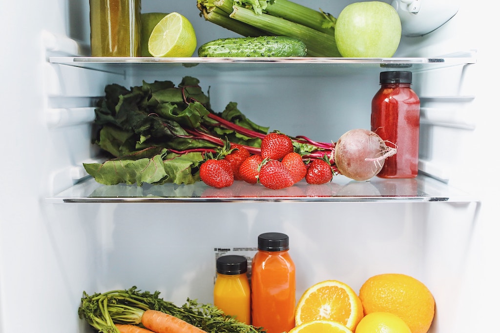 Frutas e legumes coloridas dentro de uma geladeira branca.
